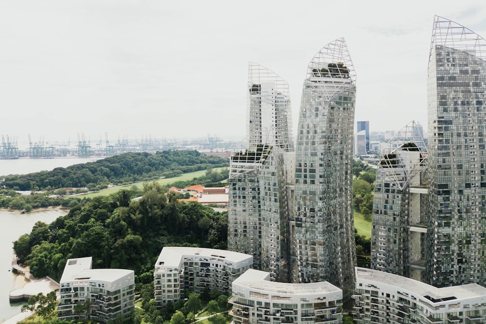 gray metal framed clear glass skyscrapers in the middle of green tree covered island near body of water under gray skies