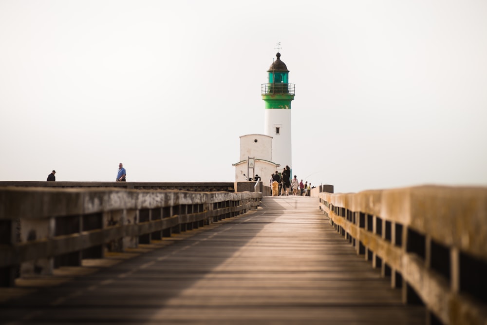 person standing white and green lighthouse