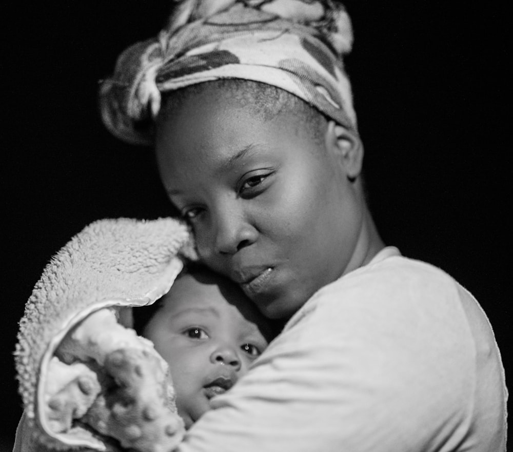 Foto en escala de grises de mujer cargando bebé