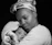 Softly lit photo of a mother gently holding her baby wrapped in a taupe-colored blanket.