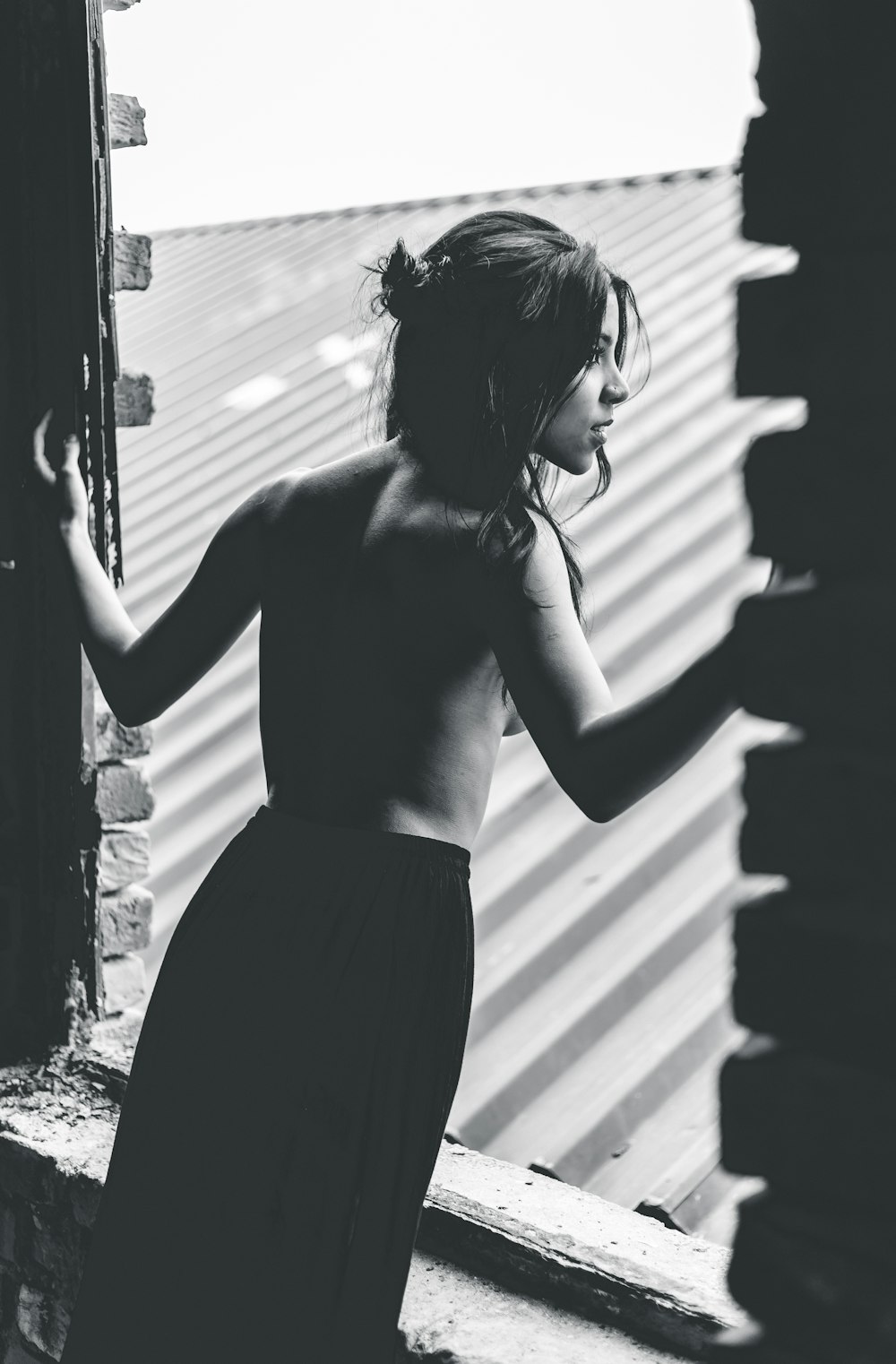 grayscale photo of topless woman standing on window