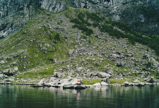 body of water beside gray and green mountain during daytime in Lysefjord Norway