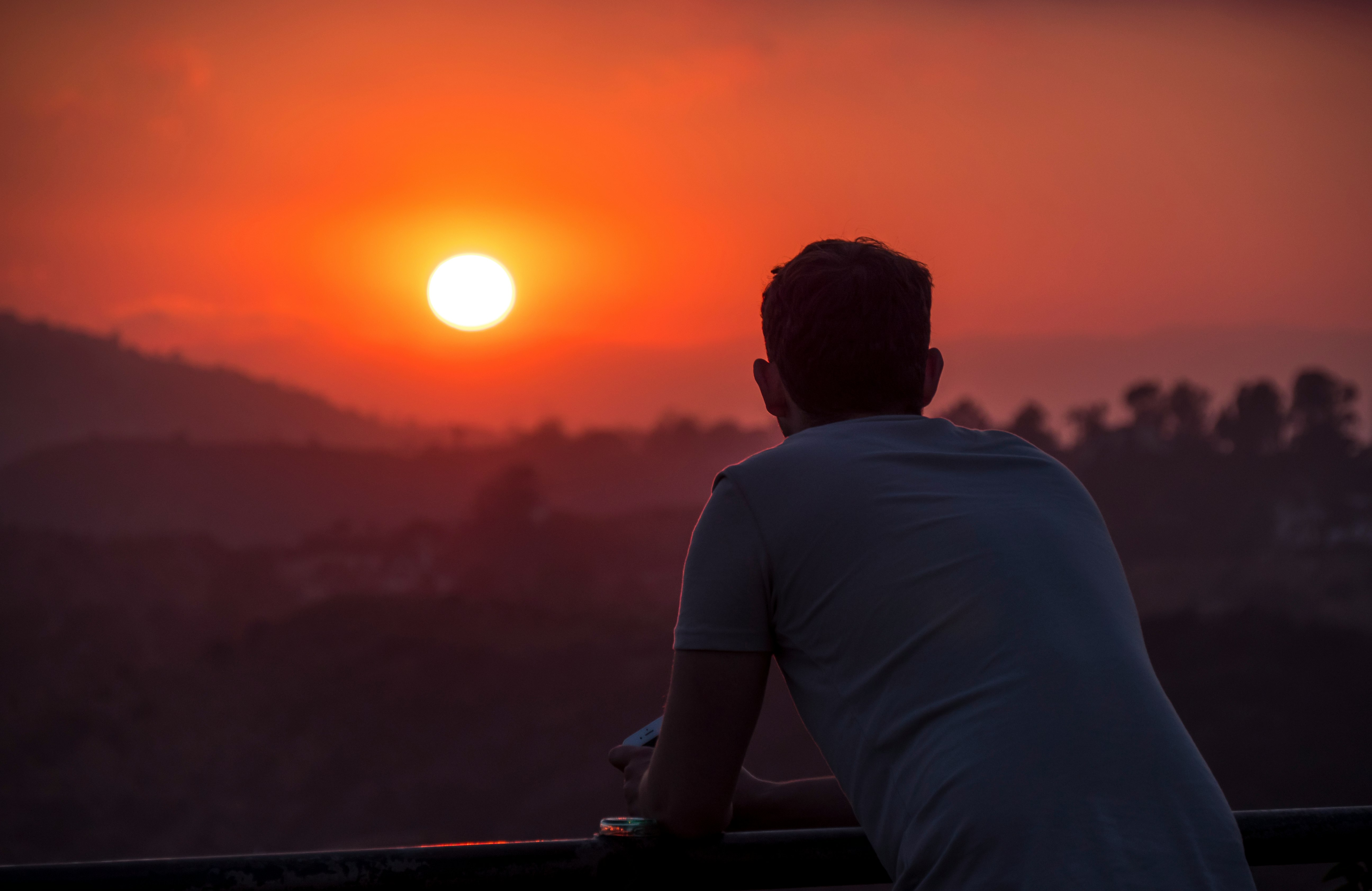 man wearing blue shirt looking at sunset