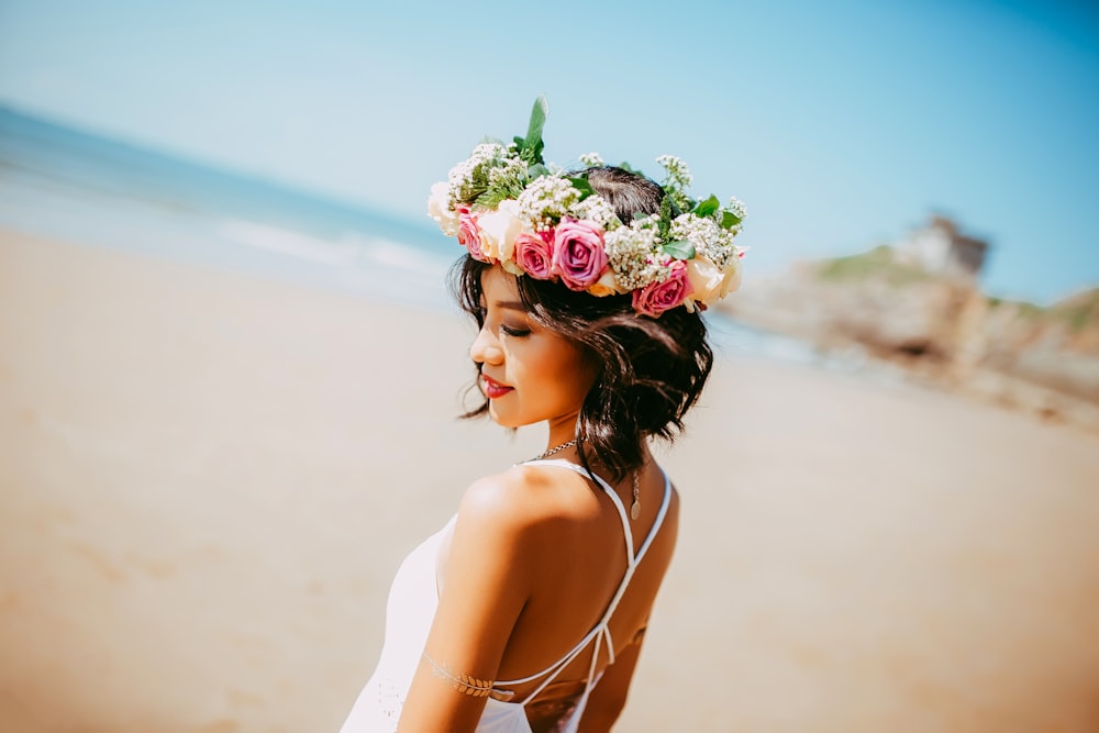 昼間、海岸で白いホルタードレスと花柄のティアラを身に着けた女性