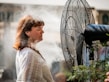 A person enjoying a refreshing breeze from a portable fan at a picnic.