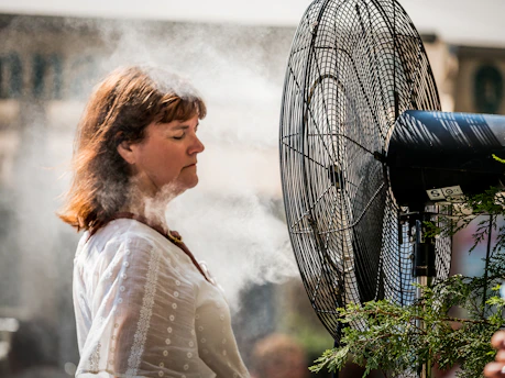 A refreshing misting fan cooling down a lively outdoor event in Banda Aceh under the bright sun.
