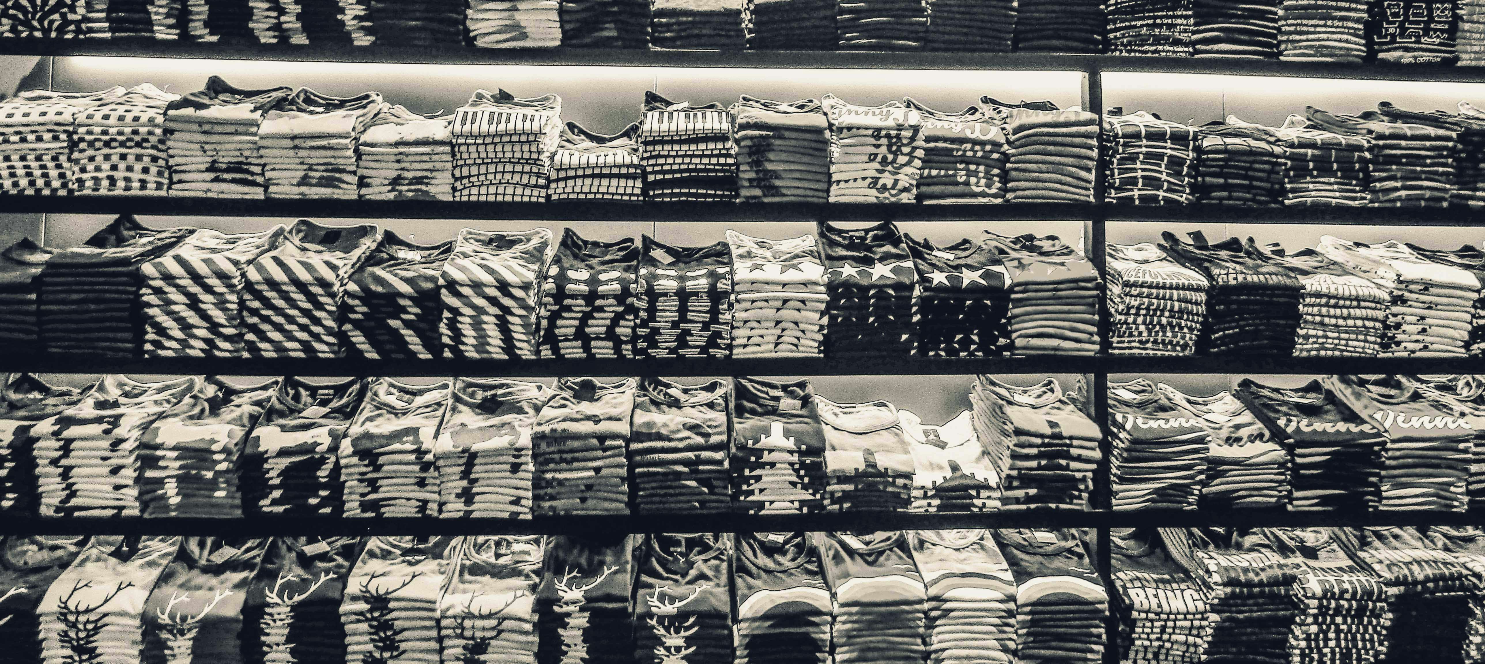Bright retail display with neatly folded colourful garments on white shelves, warm even studio lighting