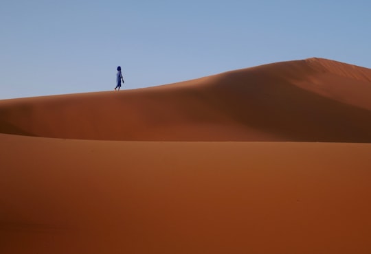 silhouette of person walking on desert in Erg Chebbi Morocco
