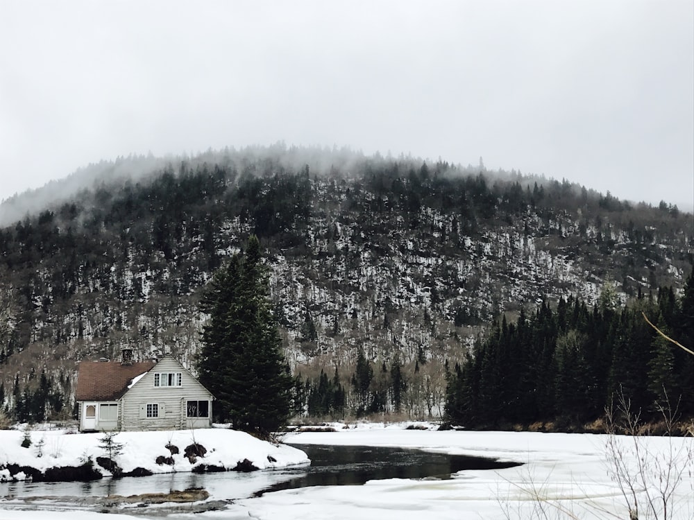 white house near river surrounded by snow-covered land