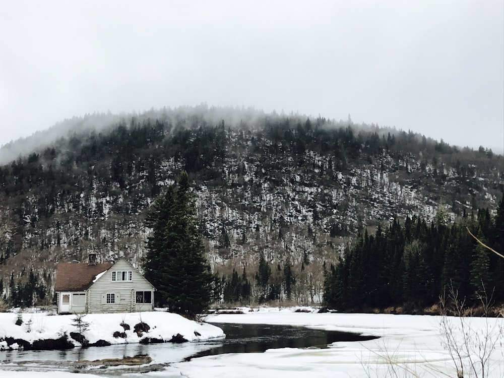 Casa blanca cerca del río rodeada de tierra cubierta de nieve