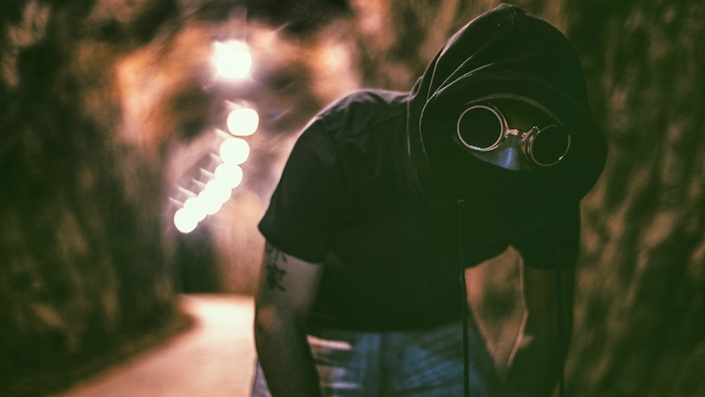 homme avec des tatouages de biceps avec du texte kanji portant un sweat à capuche noir et un bas en jean bleu