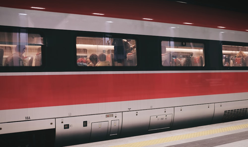 Gruppo di persone all'interno del treno rosso e grigio