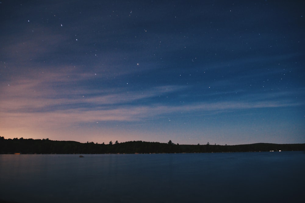 the night sky is lit up over a lake