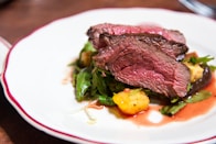 medium rare sliced steak in white ceramic plate