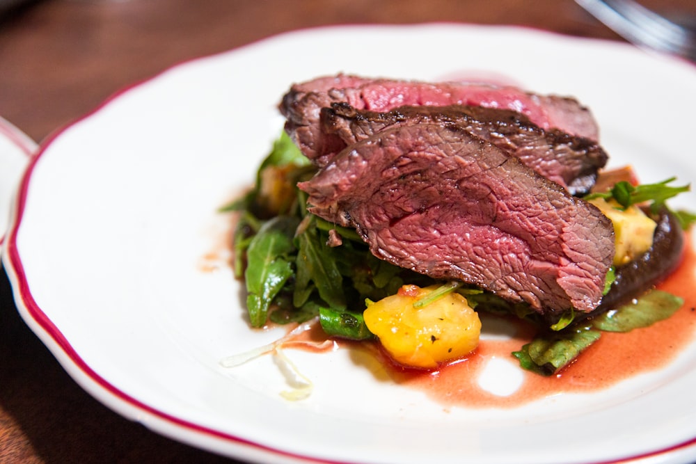 medium rare sliced steak in white ceramic plate