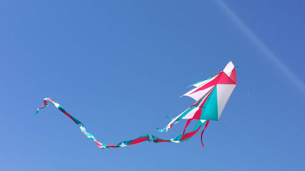 photo of white, blue, and red kite under blue sky