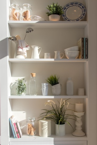 Neatly arranged kitchen and storage containers on white shelves with soft natural light.