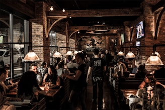 A lively interior shot of pub 15 with patrons enjoying burgers and drinks under warm lighting against gray and black decor.