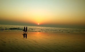 A serene sunset silhouette of two people walking side by side on a beach