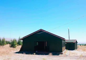 A rustic cabin nestled among desert scrub with solar panels on the roof under a clear blue sky.
