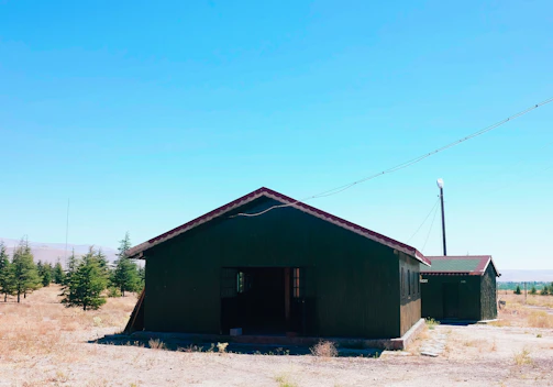 A rustic cabin nestled among desert scrub with solar panels on the roof under a clear blue sky.
