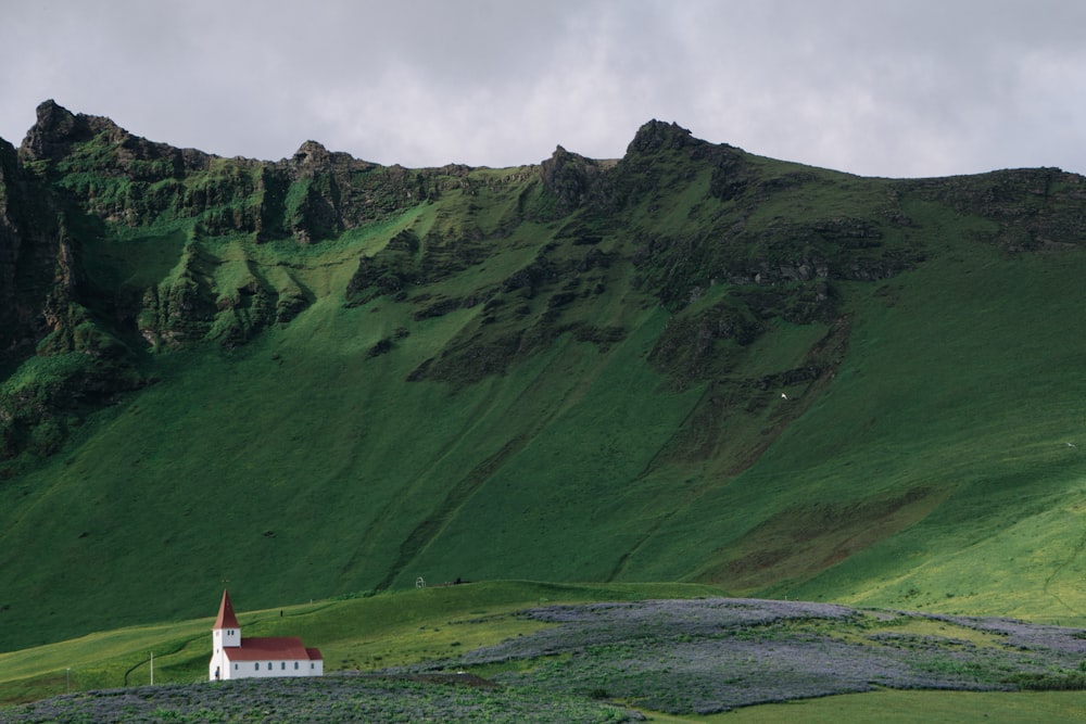 Edificio in cemento bianco e rosso vicino alla montagna verde del campo dell'erba durante il giorno