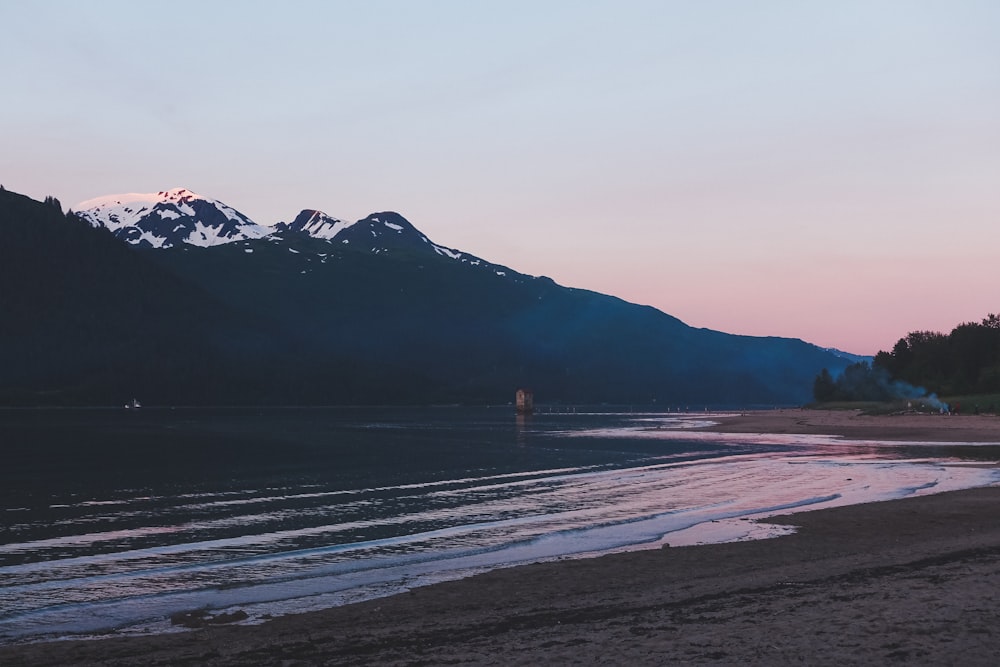 seashore near mountain covered by snow