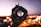 A close-up of a camera lens reflecting a vibrant cityscape at dusk with red accents.