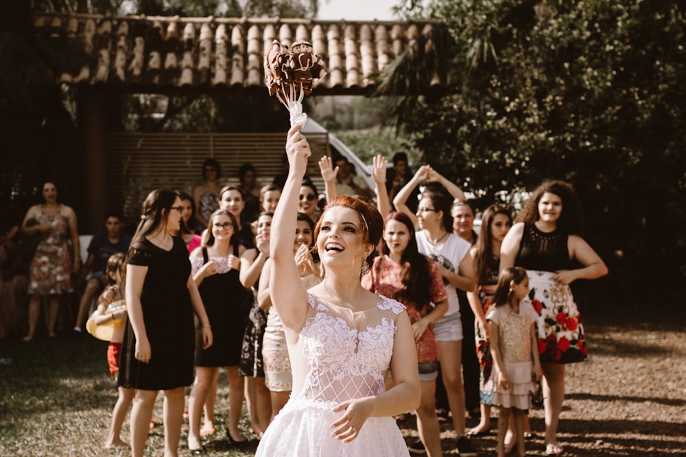 bride throwing flower bouquet on women during daytime