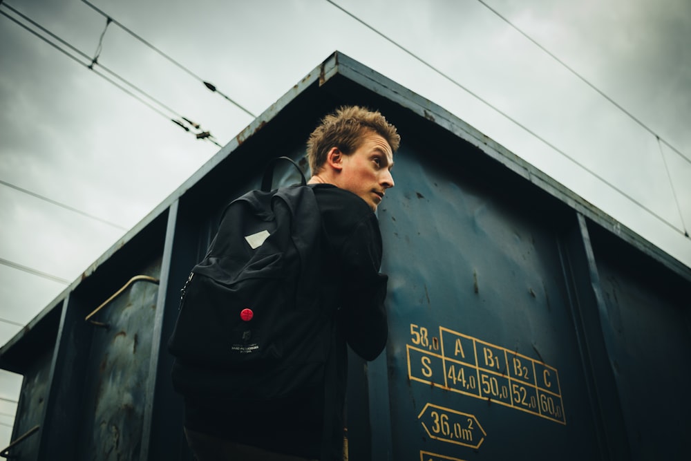 man wearing black backpack beside building