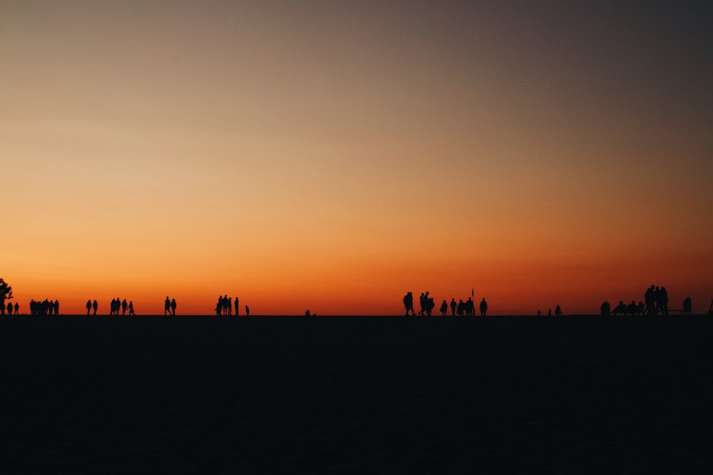 silhouette de personnes debout à travers le coucher du soleil