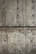 A textured concrete wall with visible holes possibly left from formwork and dark streaks of water or stains running vertically. The surface shows various shades of gray and brown, indicating wear and aging.