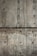 A textured concrete wall with visible holes possibly left from formwork and dark streaks of water or stains running vertically. The surface shows various shades of gray and brown, indicating wear and aging.