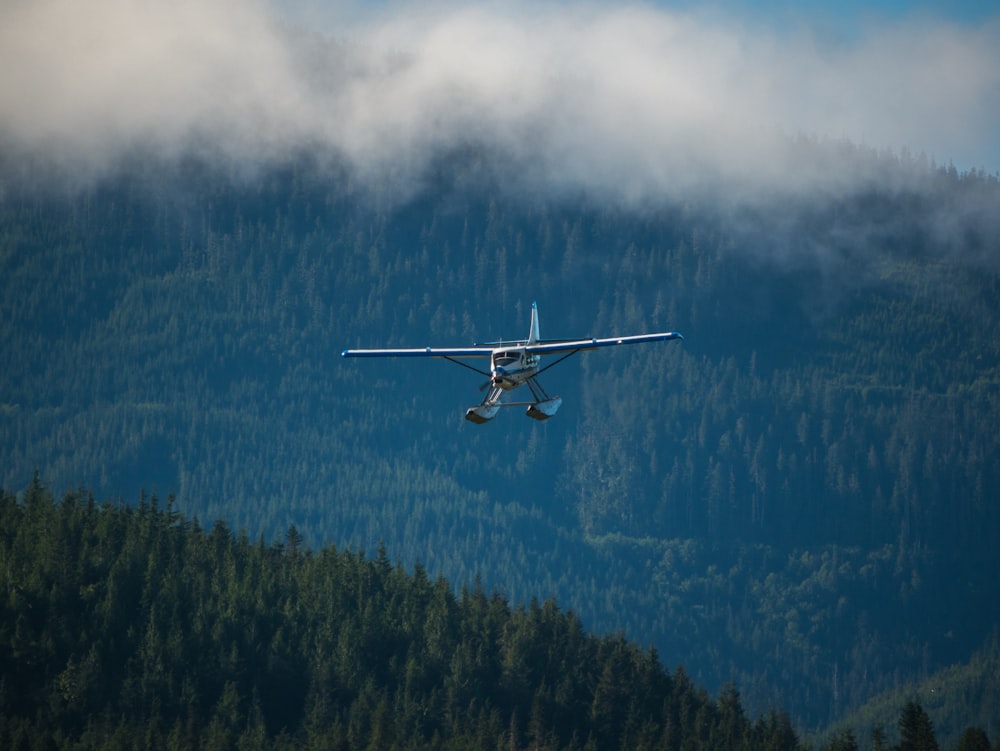 airplane above mountain covered in trees