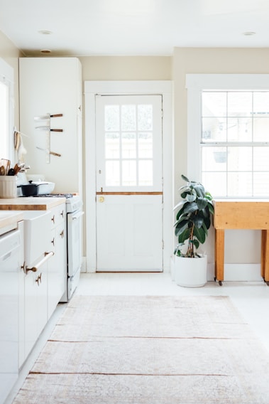 Bright, airy kitchen with white marble countertops and soft gold hardware glowing in natural light.