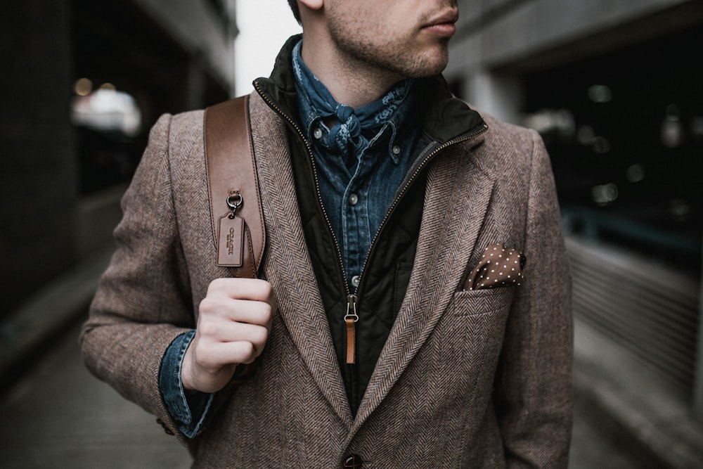 man in brown suit jacket carrying brown backpack