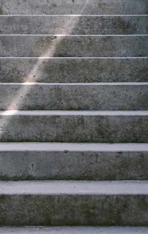 Finishing touches being applied to a smooth concrete step under natural daylight highlighting texture.