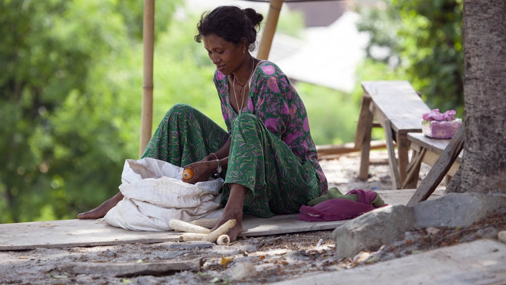 a woman sitting on the ground next to a bag of food