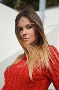 woman wearing red knit shirt with her hair being flown by the wind selective focus photo