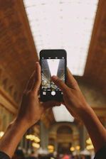 Person taking a photo of an interior corner with a smartphone.