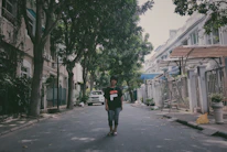 Joshua walking through a quiet Chicago neighborhood street lined with trees and classic Midwestern homes.