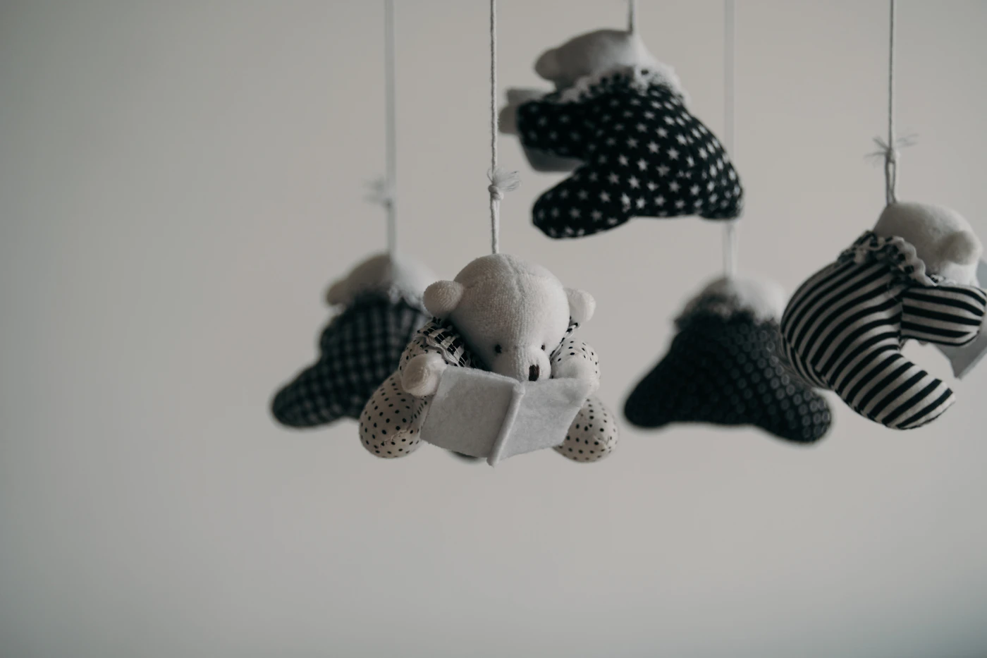 White crib with a mobile hanging above it in a plain, uncluttered nursery