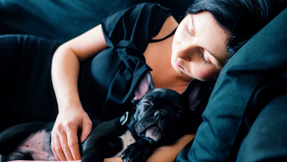 Frau und schwarze französische Bulldogge schlafen auf dem Sofa