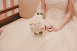 Soft-focus image of a bride holding a bouquet, her rings catching the sunlight.