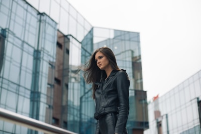 A model wearing a sleek black leather jacket standing against a city backdrop.