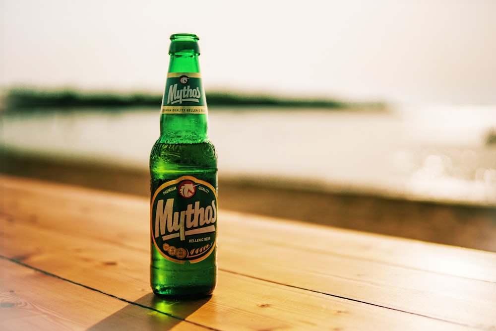 Garrafa de cerveja Mythos na mesa de madeira perto da praia