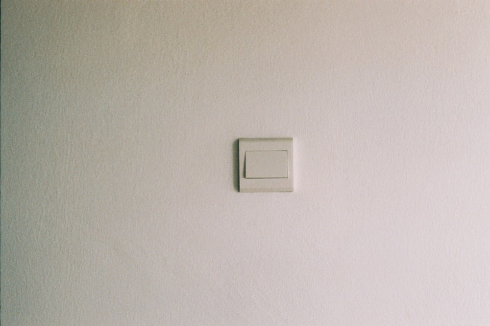 Interruptor de luz blanca en la pared pintada de blanco