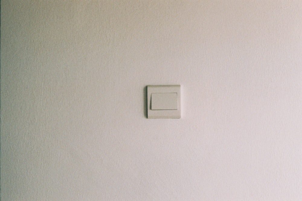 Interrupteur de lumière blanche sur mur peint en blanc