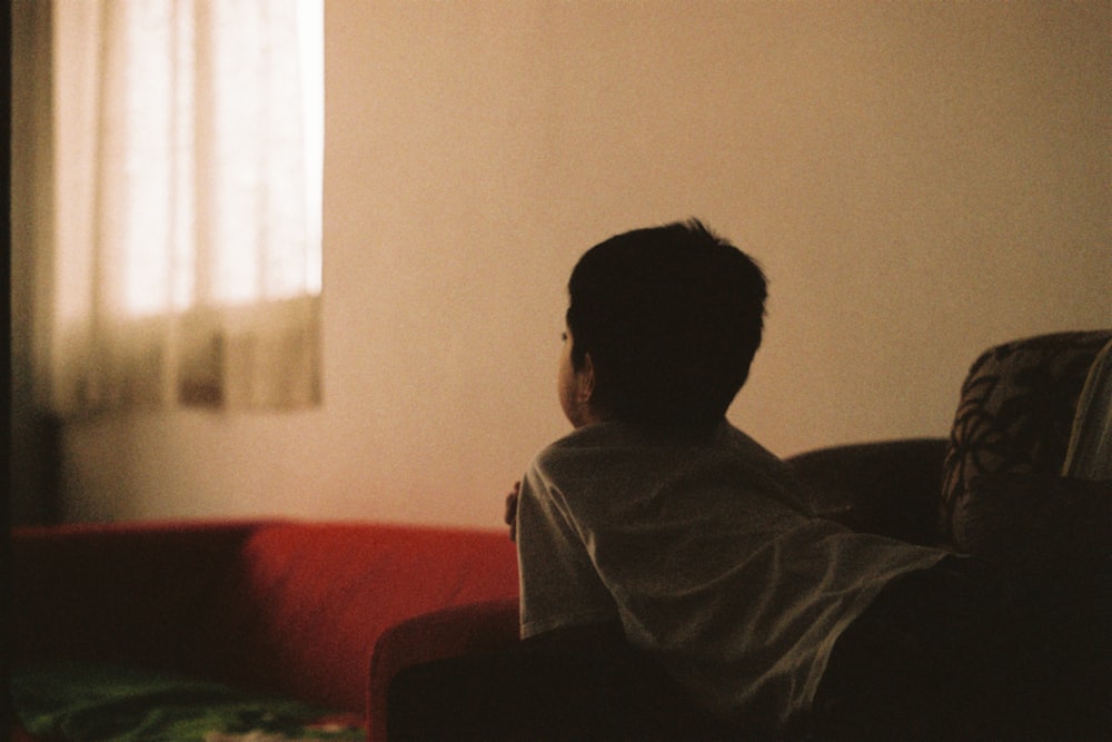 man in gray shirt sitting on red couch