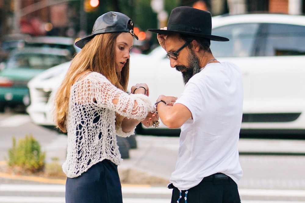 men and woman standing near road during daytime photography